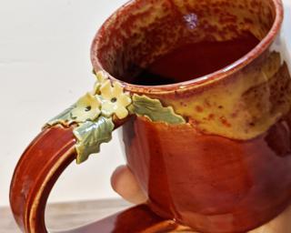 A curvy ceramic mug with a sweet little bunch of flowers on top of the handle.