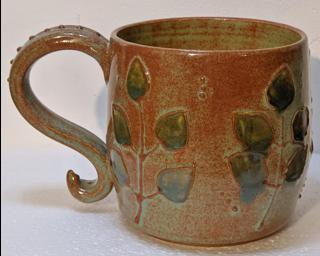 A lovely ceramic mug with a gorgeous textured branch design around the outside and finished with rustic green and blue glazes.