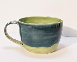 A lovely ceramic mug with lovely combination of blue and green glazes around the outside.