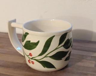 Hand stenciled leaves and berries on a ceramic mug.