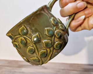A lovely ceramic mug with ivy vines wrapped around the outside.