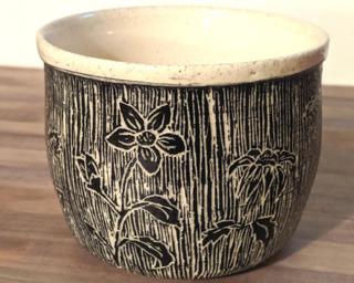 Accessorize your home with this hand carved ceramic planter with a unique floral design.