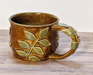 A lovely ceramic mug with leaf sprigs around the outside and on the handle.