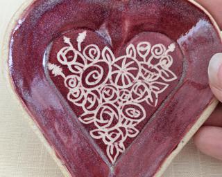 A small handmade heart-shaped dish decorated with a dozen little roses.