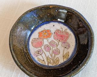 A little handmade square dish decorated with a variety of colorful flowers which have been carefully carved for added detail.