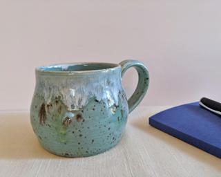 A lovely ceramic mug with unique blend of drippy glazes around the outside.