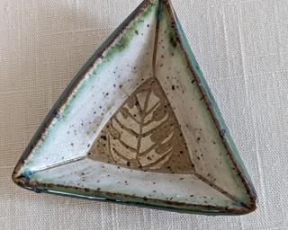 A small handmade oblong-shaped dish decorated with a single monstera leaf which has been carefully carved for added detail.