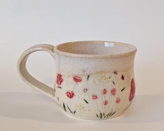 Mug with hand-painted flowers and a creamy white glaze on the inside and around the rim.