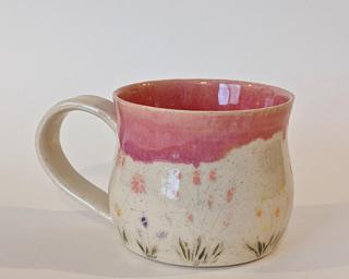 Mug with hand-painted flowers and a pink glaze on the inside and around the rim.