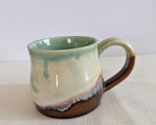 A lovely ceramic mug with unique blend of drippy glazes around the outside.