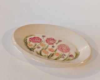 A little handmade square dish decorated with a variety of colorful flowers which have been carefully carved for added detail.