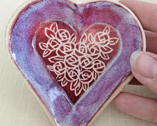 A small handmade heart-shaped dish decorated with a dozen little roses.