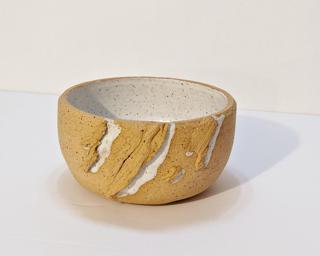 A small handle-less ceramic cup with a white glaze over a mid-fire speckled clay.