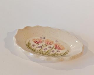 A little handmade square dish decorated with a variety of colorful flowers which have been carefully carved for added detail.