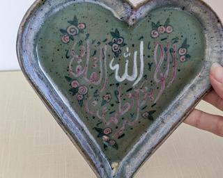 A pretty handmade heart-shaped dish decorated with Arabic calligraphy.