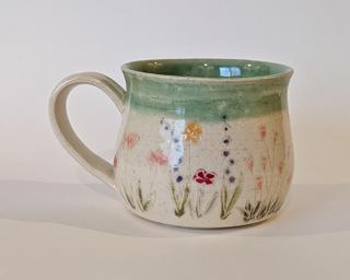 Mug with hand-painted flowers and a green glaze on the inside and around the rim.