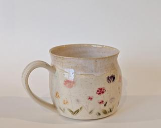 Mug with hand-painted flowers and a creamy white glaze on the inside and around the rim.