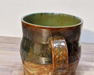 A curvy ceramic mug with an interesting blue glaze on the outside and a stamped handle.
