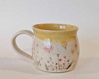 Mug with hand-painted flowers and a yellow glaze on the inside and around the rim.