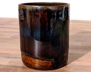 A small dark blue cup with an almost oil slick like sheen to it.