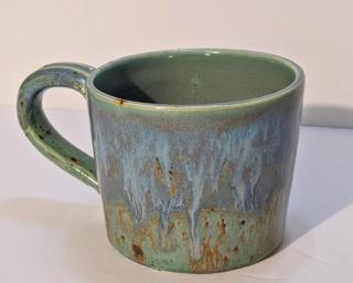 A lovely ceramic mug with unique blend of drippy glazes around the outside.