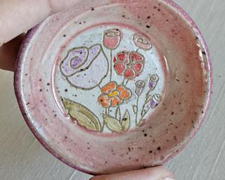 A little handmade square dish decorated with a variety of colorful flowers which have been carefully carved for added detail.