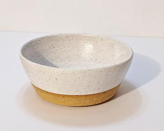 A small handle-less ceramic cup with a white glaze over a mid-fire speckled clay.
