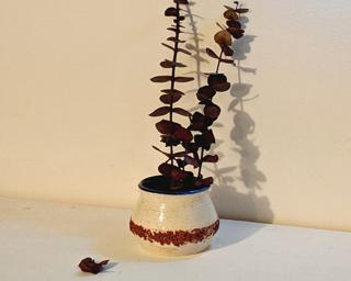 Adorn your home with this one of a kind white planter with a stripe of crushed red clay around the middle.