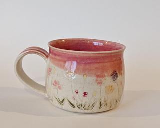 Mug with hand-painted flowers and a pink glaze on the inside and around the rim.